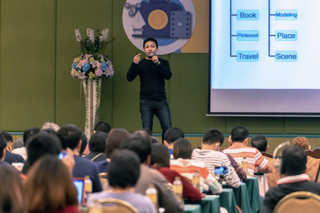 Asian Speaker with casual suit on the stage present the screen in the conference hall