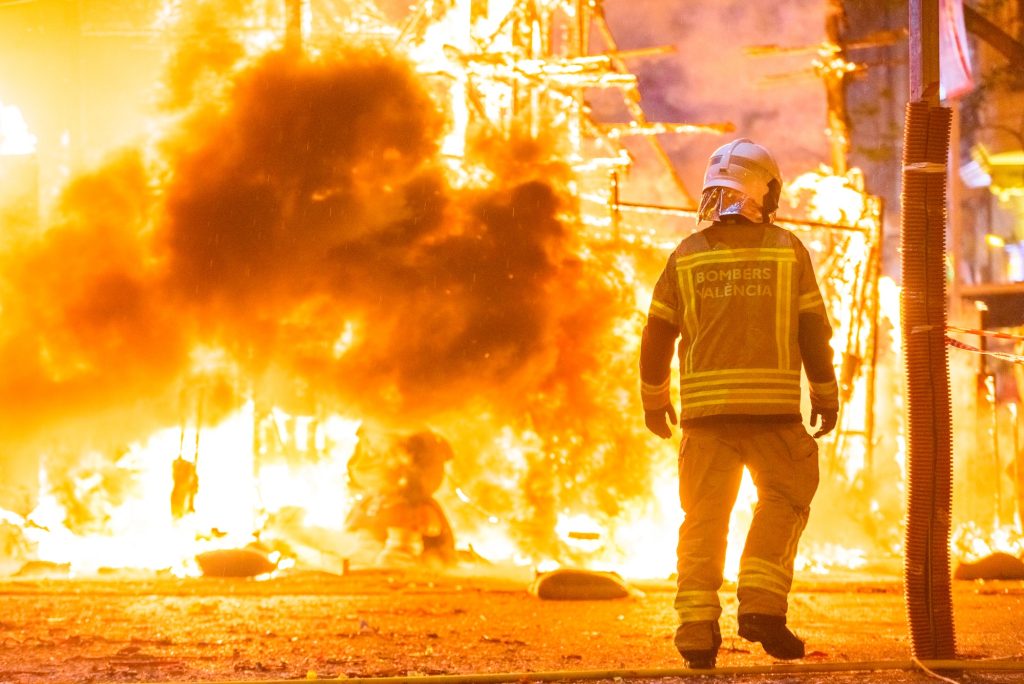 Silhouette of fireman trying to control a fire in a street during a night.